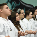 Students singing in choir with white robes on