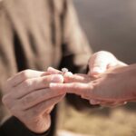 Man putting engagement ring on woman's hand