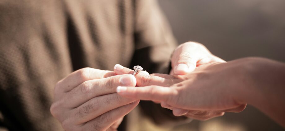 Man putting engagement ring on woman's hand