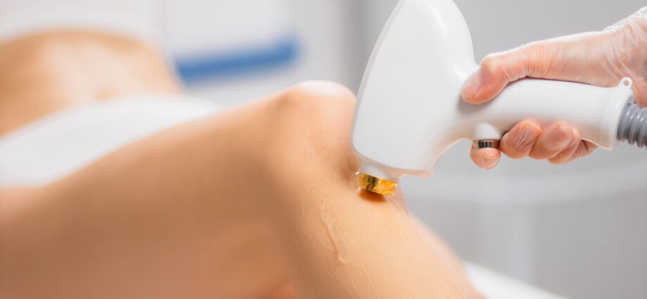 close-up photo of young woman getting laser hair removal procedure on her legs in modern clinic. cosmetology and spa, skin care concept